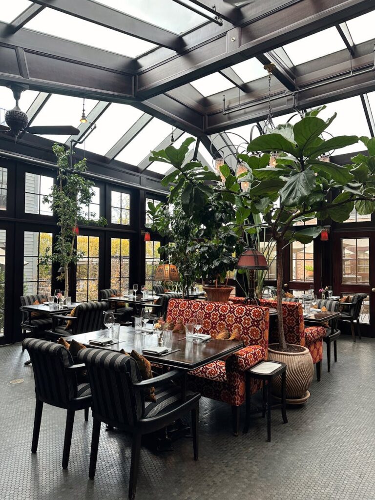 A stylish greenhouse cafe with lush greenery in Hudson, NY, offering a cozy ambiance.