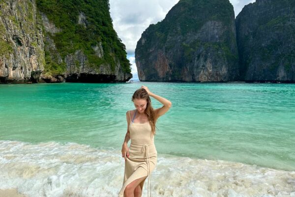 Woman walking on the beach with cliffs at Maya Bay, Thailand.