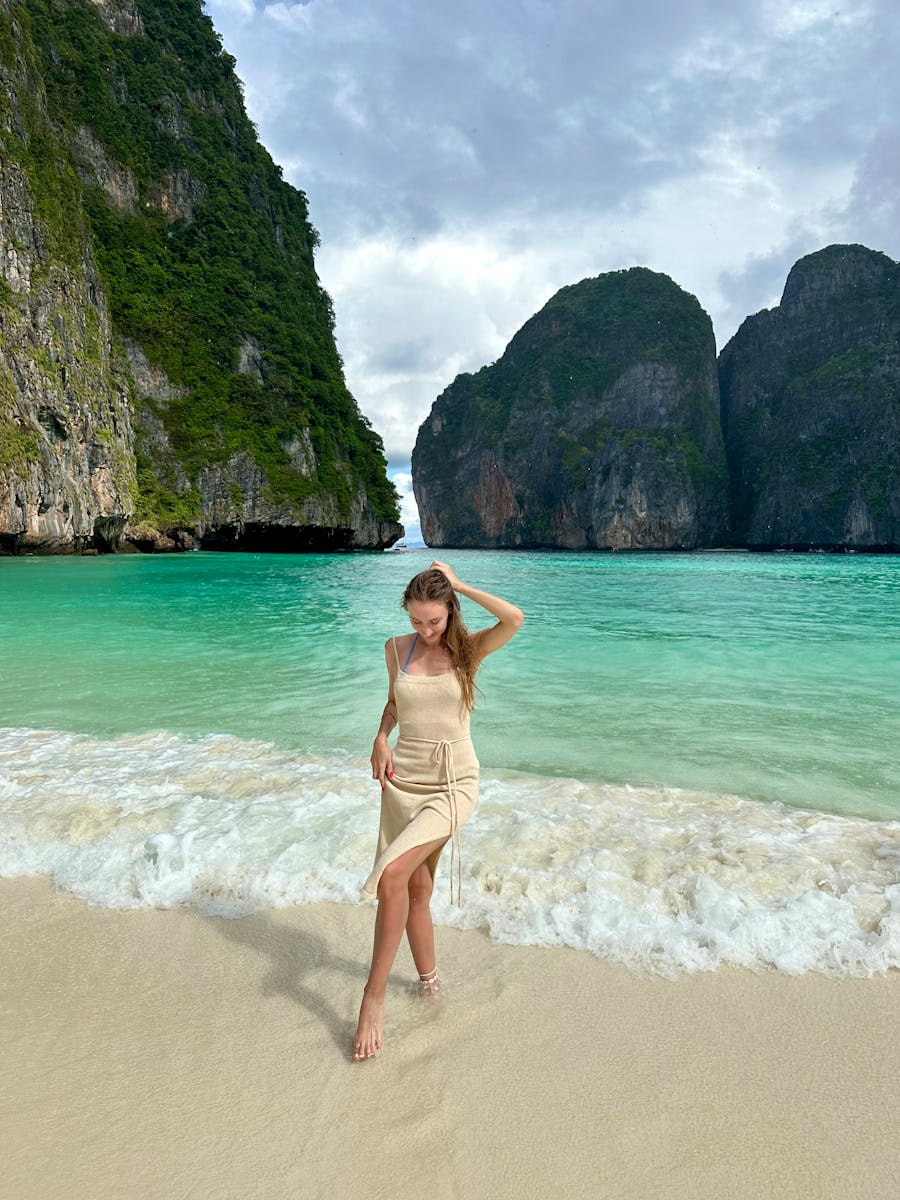 Woman walking on the beach with cliffs at Maya Bay, Thailand.